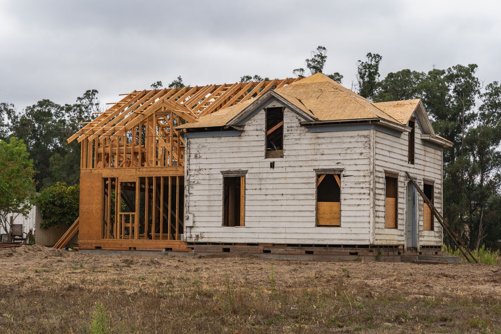 An older house mid-rebuild with new timber framing rising beside the original siding